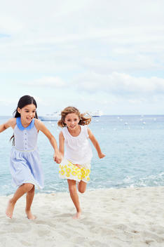 two girls holding hand running of the beach
