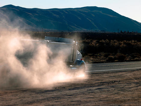 Truck Raising Dust On A Road Through The Mojave Desert