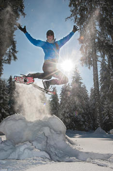 Austria, Salzburg State, Altenmarkt-Zauchensee, Man with snowshoes jumping in winter landscape