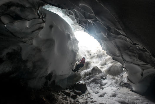 A scientist ascends a rope to exit a steam cave.