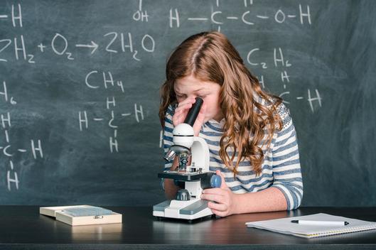 Girl (10-12) looking through microscope