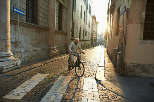 elder italian man riding a bicycle in a historical centre of a renaissance town