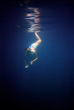 A Young Women Swims Under The Water Wearing A Snorkel And Mask.