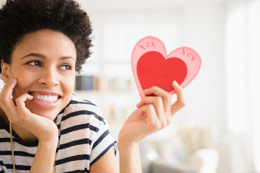 Black woman holding heart-shape Valentine