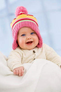 Baby girl in woolly hat, smiling, close up