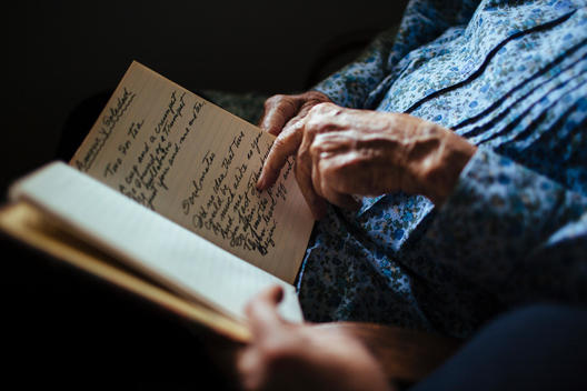 Senior woman and younger woman\'s hands looking through a journal.
