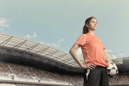 Female soccer player standing inside a stadium