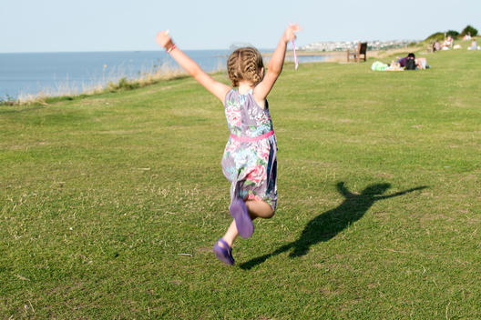 A young girl of five jumps for joy near the seaside town of Whitstable