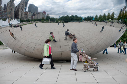 A Family Walks Past Chicago'S Cloud Gate Sculpture In Millennium Park On A Cool Day.