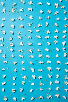 Popcorn pieces are laid in lines across a bright blue background.
