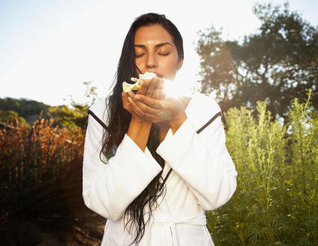 Hispanic woman smelling Gardenia flower