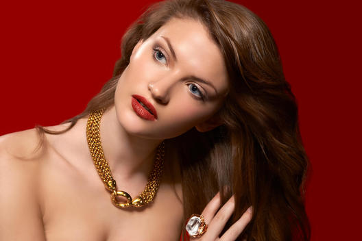 Young Woman With Open Dark Blond Hair And Red Lips Wearing Gold Necklace And Diamond Ring.