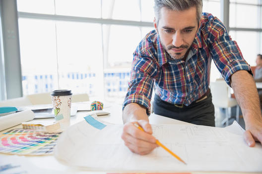 Creative businessman looking at blueprint in office