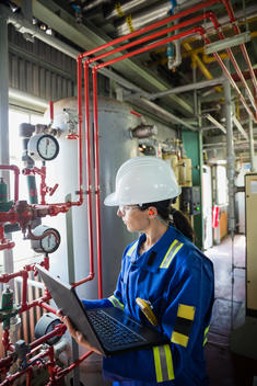 Female worker with laptop in gas plant