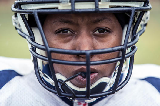A close up portrait of a women\'s football player wearing her helmet prior to the start of a game.