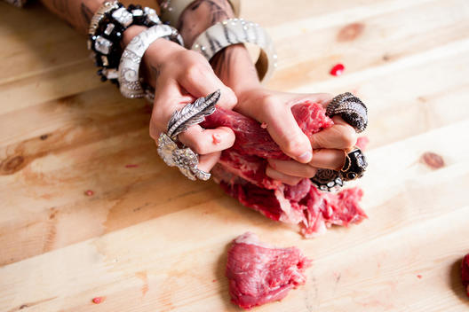 Hands tearing raw meat