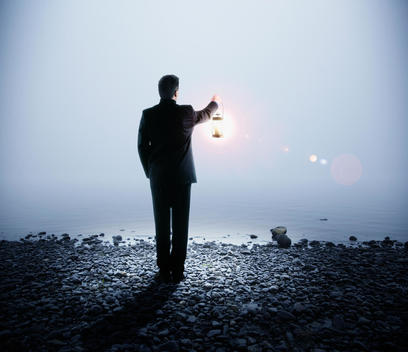 Portuguese businessman holding lantern next to water