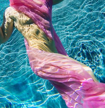 Woman draped in fabric swimming semi-naked underwater