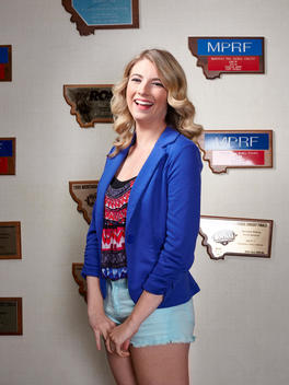 Brenna Gree standing in front of plaques of recognition and awards at station