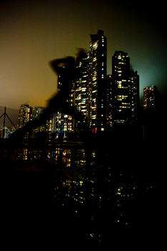 Silhouette of person jumping in the air with city buildings in background.
