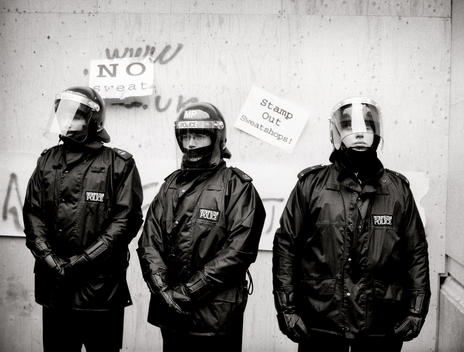 Met Police officers stand in riot gear in front of Nike Town in Oxford Circus which had been boarded up to protect it from vandalism during anti-capitalism march, \'Reclaim the Streets\' / May Day Protest, London. UK.