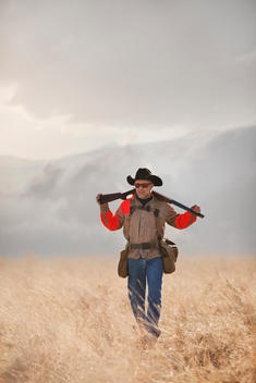 Pheasant hunter walking through fields with over under shotgun broken over his shoulders
