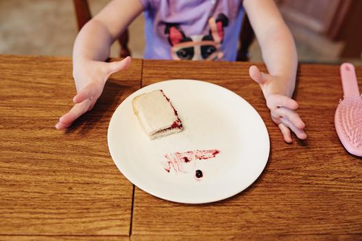 Girl eating peanut butter and jelly sandwich.
