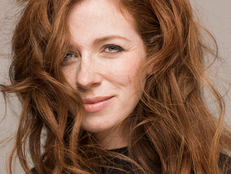 Tight crop of a red headed woman with messy wind swept hair.