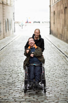 Caretaker pushing disabled man on wheelchair at city street