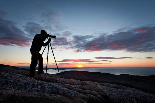 Silhouette Of A Photographer Taking Photos Of The Ocean At Sunrise, Acadia National Park, Bar Harbor, Maine, Usa.