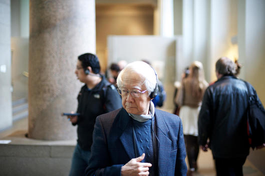A male Japanese tourist listening to a guided tour on headphones in the British Museum in London