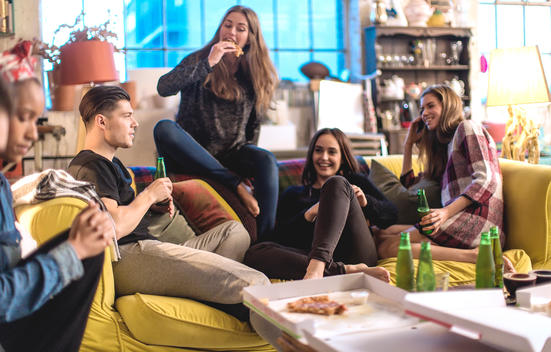 boy and girlfriends hang out together on the sofa eating beer and pizza in cool loft apartment