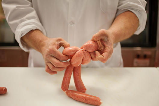 Butcher twisting and making fresh sausages.