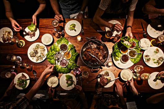 Aerial view of a table of people sharing a meal in a dimly lit space.