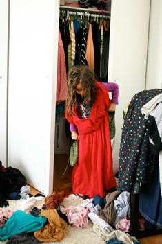 Young girl tries on mother\'s clothes in bedroom.