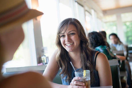 A woman sitting at a diner table holding a cool drink.