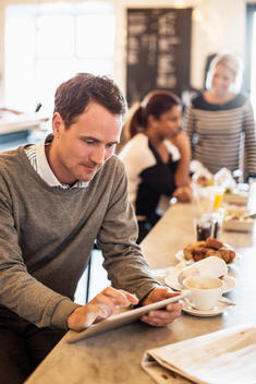 Businessman using digital tablet at table with female colleagues in background