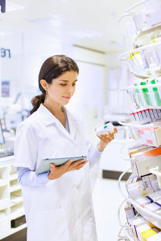 Young female pharmacist stock taking in pharmacy