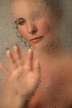 Woman Looking Through A Drawn Heart In The Steam On A Shower Window