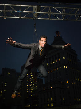 Man in his 30\'s wearing a suit, hangs from a crane above a roof top in Ney York, New York on December 07, 2012.