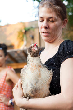 volunteer holds hen at Imani Garden chicken coop, run by BK Farmyards