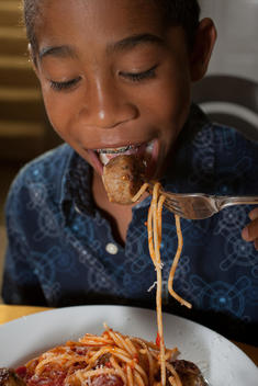 Boy Eating Spaghetti And Meatballs With A Meatball On His Fork