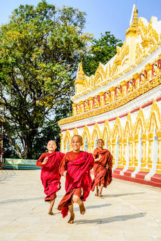 Asian monks-in-training running outside ornate temple