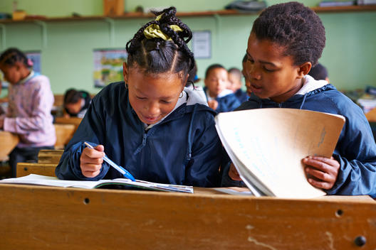 two girls at classroom desk sharing homework