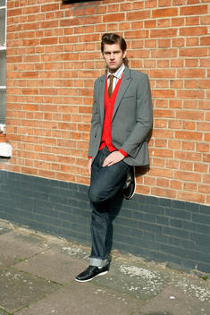 Male Fashion Model In Formal Attire Casually Leaning On Wall