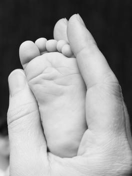Mother holding new born baby\'s foot.