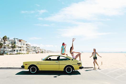Girls running towards a vintage car.