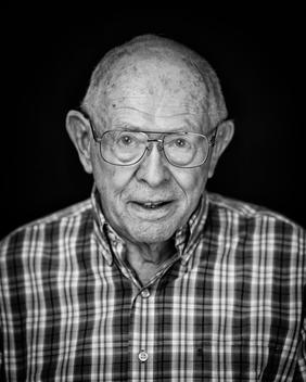 Black and white portrait of elderly man wearing glasses plaid shirt