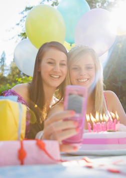 Teenage girls at birthday party taking a self portrait with mobile phone