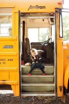 girl sitting on the steps of the school bus